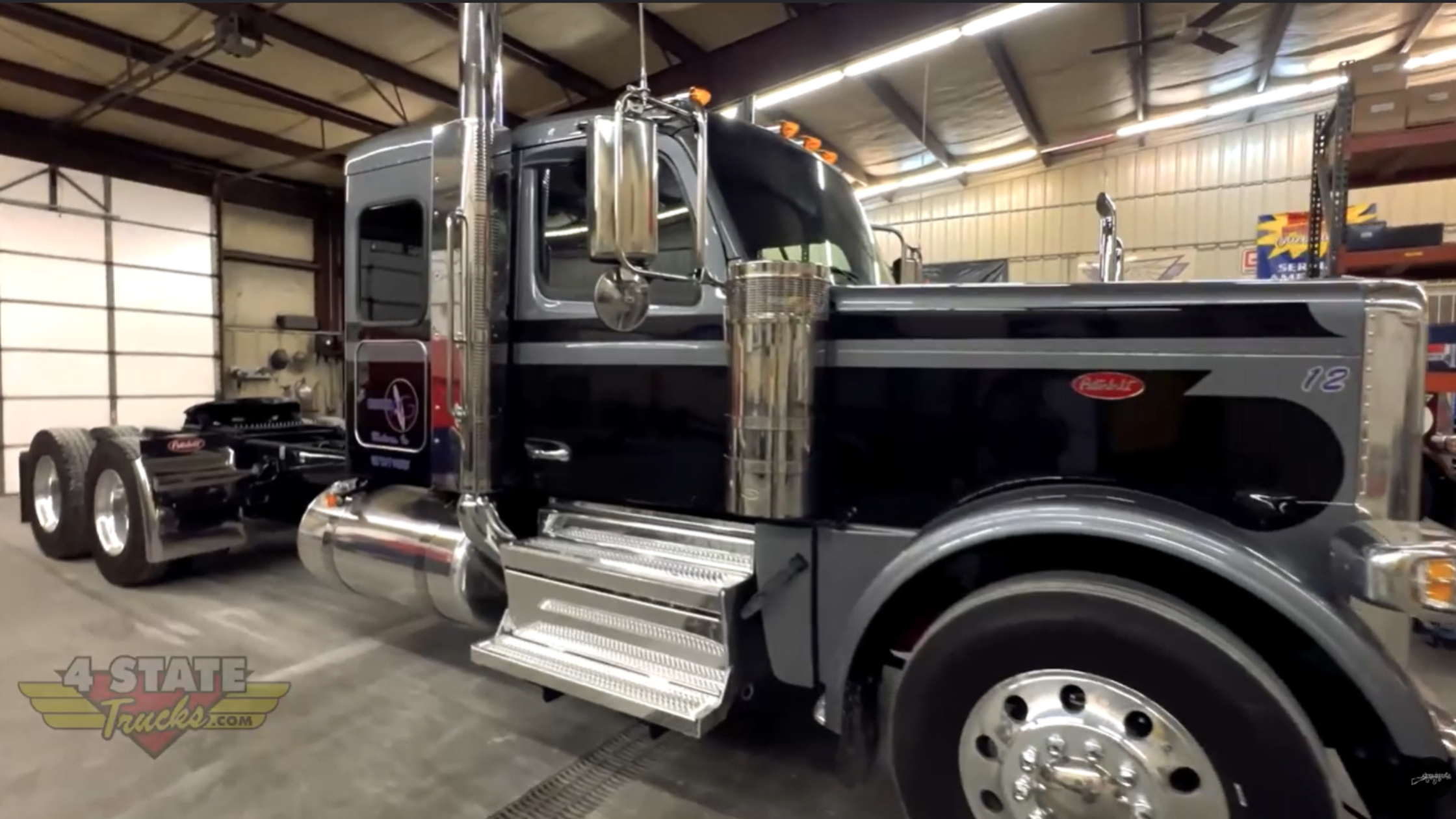 Flat roof Peterbilt 589 parked inside Chrome Shop Mafia installation bay in Joplin Missouri before custom visor and exhaust upgrades.