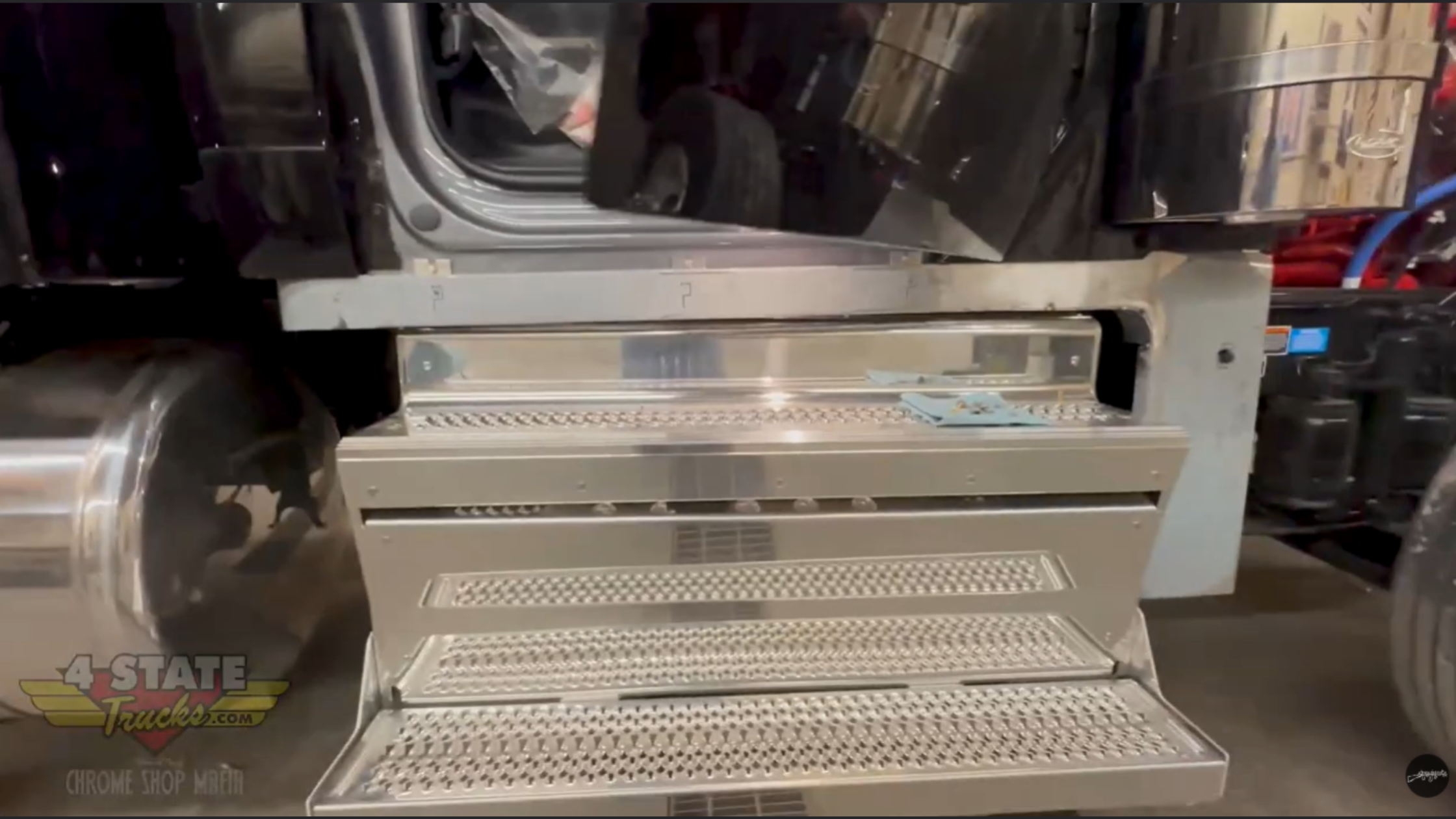 Aluminum step assembly on Peterbilt 589 showing factory tread plate steps before stainless trim and lighting upgrades.