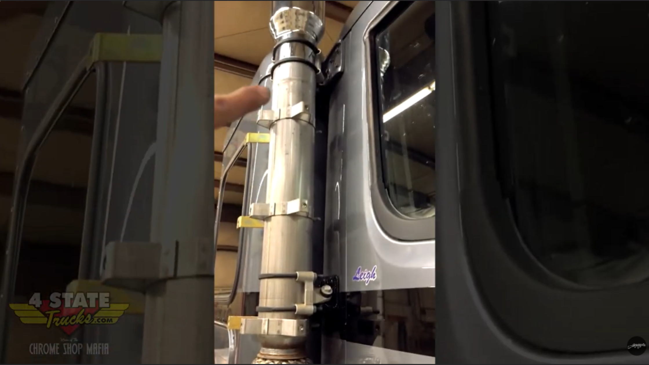 Close-up of factory exhaust stack and mounting brackets on Peterbilt 589 showing multiple clamps and upper cab connection point.